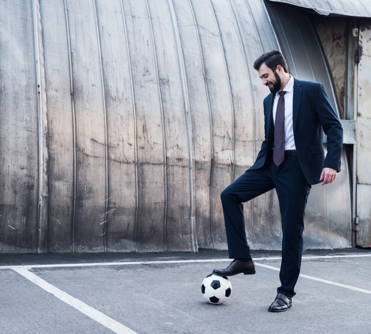 Mann im Anzug spielt Fußball